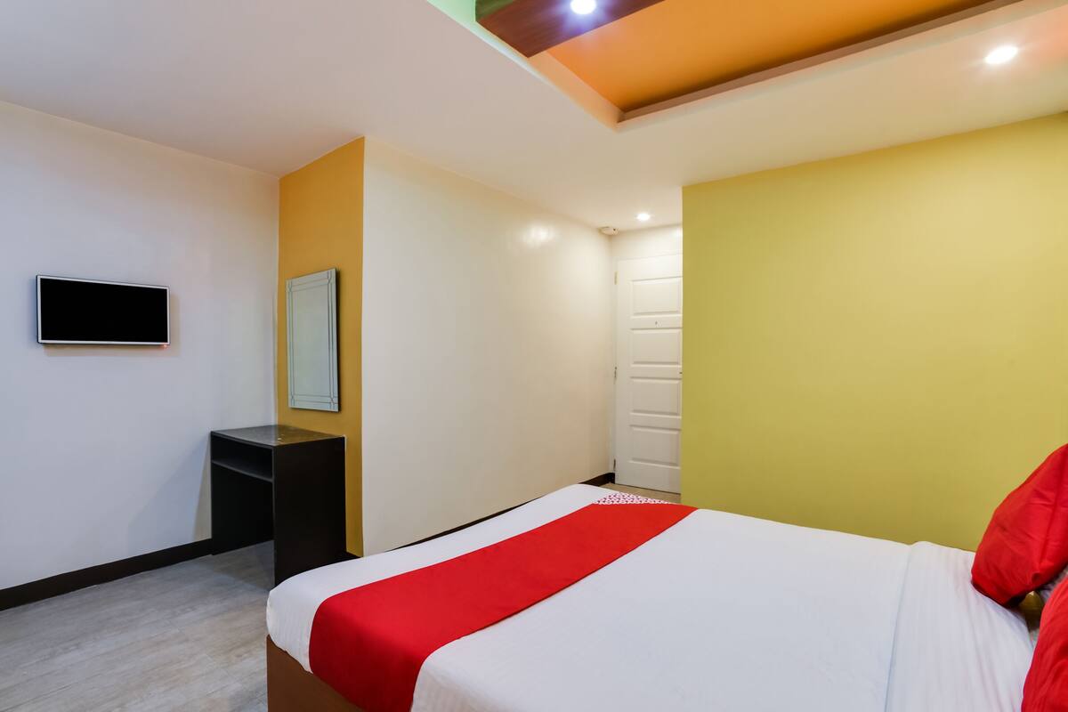 Ein Hotelzimmer mit Bett, Fernseher, Schreibtisch und Tür.