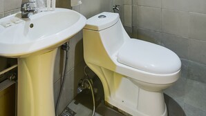 A bathroom with a sink, toilet, and a hand soap dispenser.