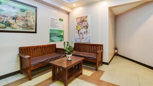 A reception area with wooden benches, a small table with a plant, and artwork on the walls. - OYO 473 Ranchotel Drive-in (Biñan City)