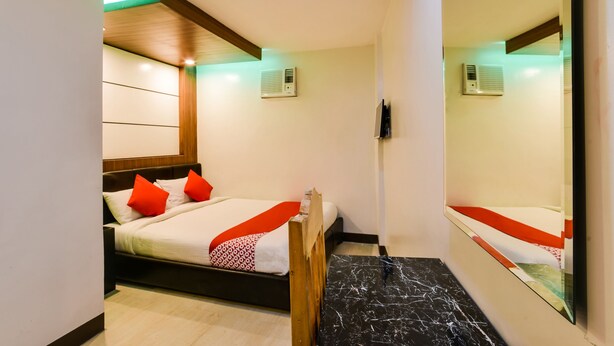 A hotel room with a bed, a wooden headboard, a red and white patterned throw, and a marble floor. - OYO 473 Ranchotel Drive-in (Biñan City)