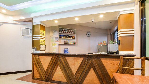 A reception area with a wooden counter, a clock, and shelves with various items.