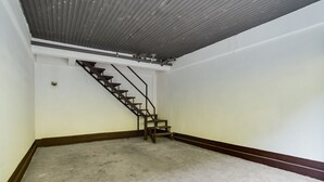 A room with a concrete floor, a wooden staircase, and a white wall with a brown baseboard. - OYO 473 Ranchotel Drive-in (Biñan City)