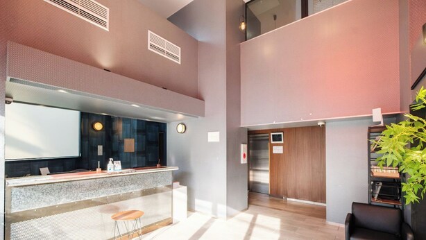 A modern hotel lobby with a reception desk, seating area, and a staircase leading to an upper level. - HomeNest Hotel Tennoji (Osaka)