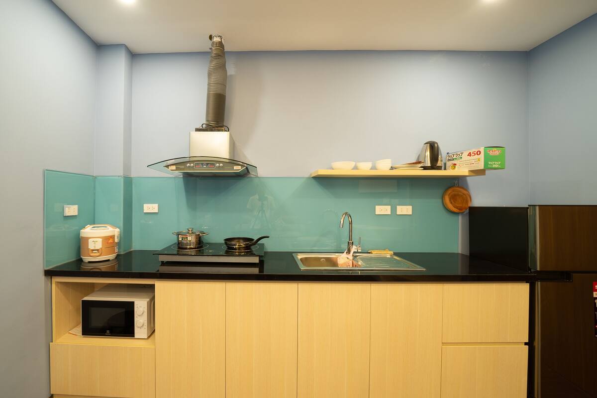 A compact kitchen with a microwave, stove, sink, and a small cabinet.