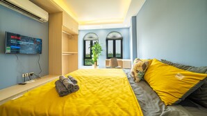 Une chambre d’hôtel avec un grand lit, un téléviseur fixé au mur, un bureau et une fenêtre donnant sur un beau paysage.