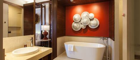 Un baño moderno con una bañera independiente, un lavamanos doble y un revestimiento decorativo con patrones circulares.
