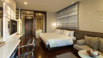 A hotel room with a bed, a sofa, a TV, and a desk.