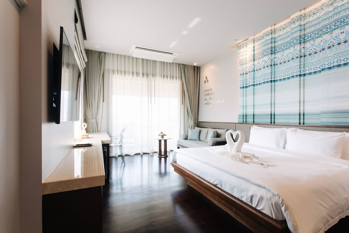 Une chambre d’hôtel moderne dotée d’un grand lit, d’un téléviseur à écran plat, d’un canapé et d’un élément décoratif mural.