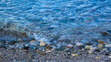 A pebbled beach with clear water and rocks.
