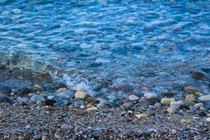 Une plage de galets avec une eau claire et des rochers.