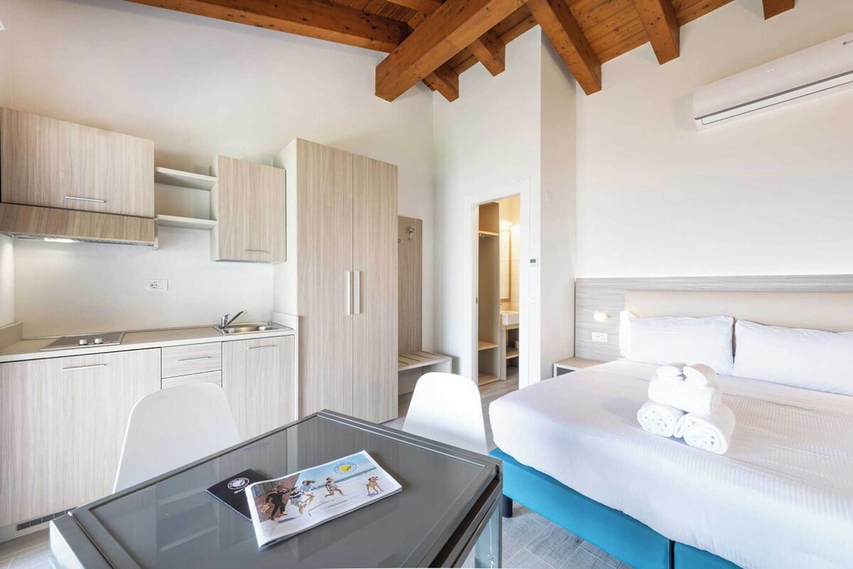 Une chambre d’hôtel comprenant un lit, une petite table, un coin cuisine et une salle de bain.