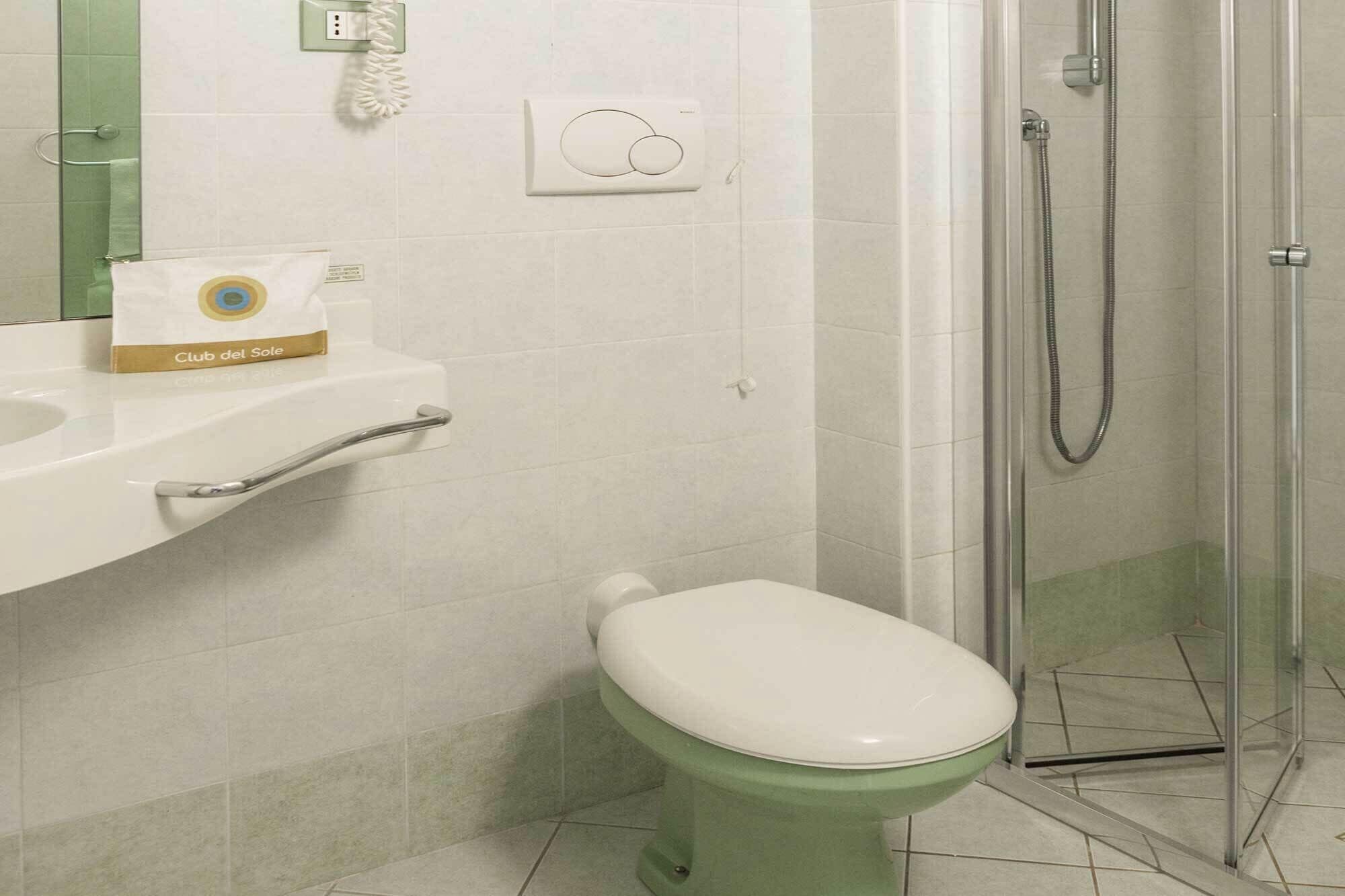 A bathroom with a toilet, a shower, a sink, and a towel rack.