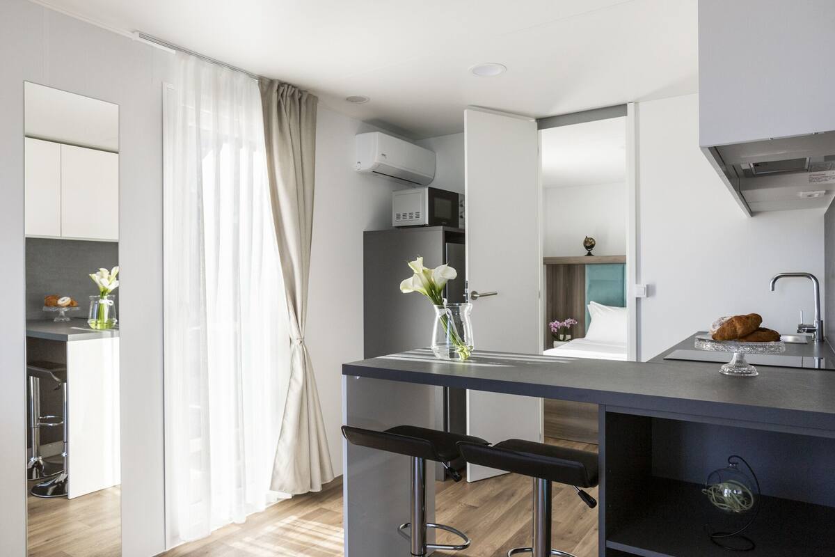 Una cocina moderna con una isla central, taburetes de bar y un refrigerador.