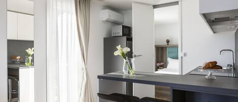 Una cocina moderna con una isla central, taburetes de bar y un refrigerador.