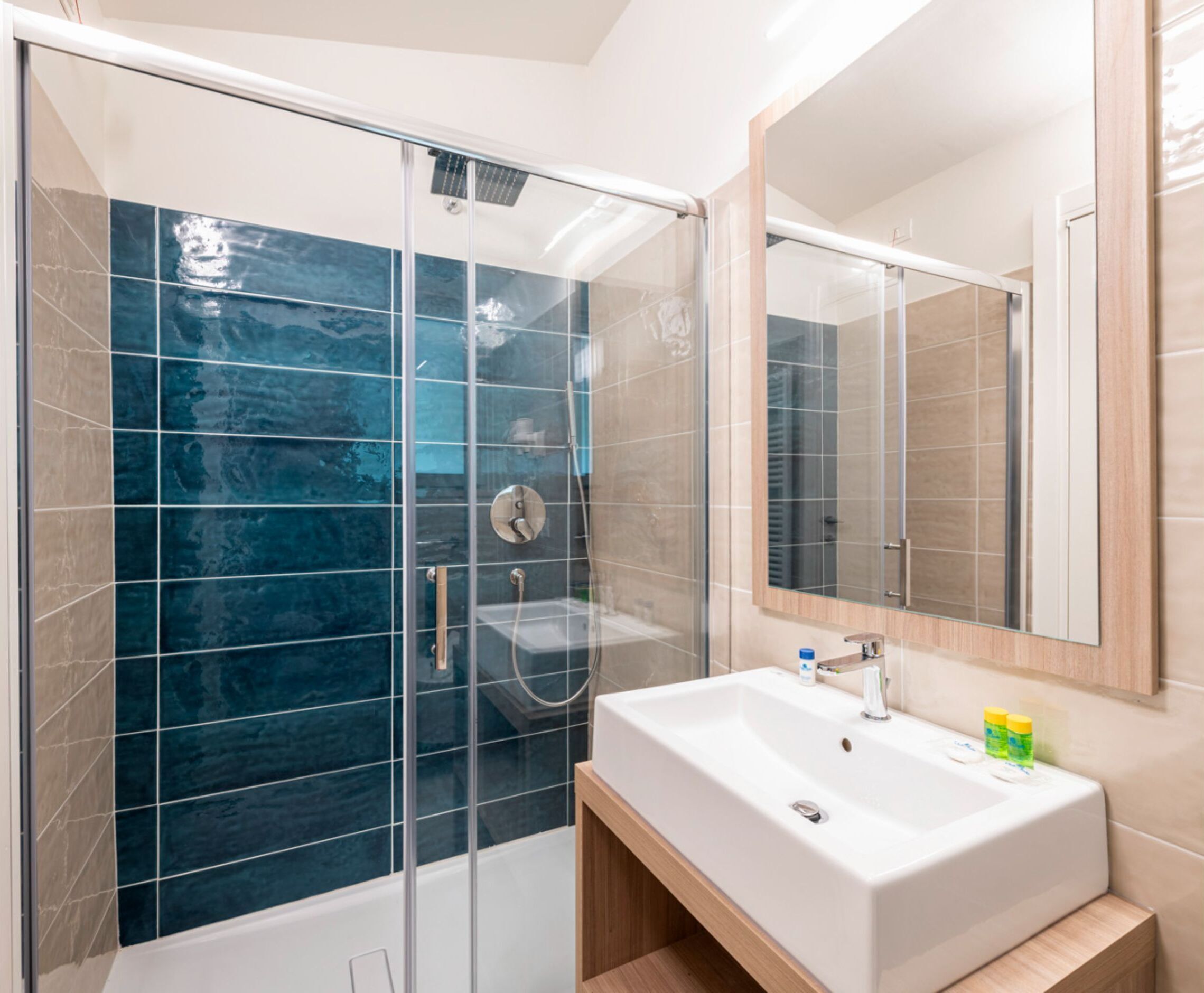 A modern bathroom with a glass-enclosed shower, a white sink, and a mirror.