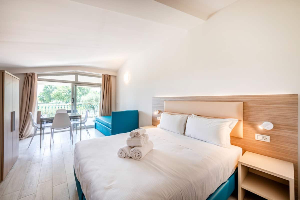 Una habitación de hotel con una cama grande, un escritorio, una silla y un balcón con vistas.