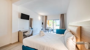 Ein Hotelzimmer mit Bett, Schreibtisch, Stuhl, Fernseher und Blick ins Freie.