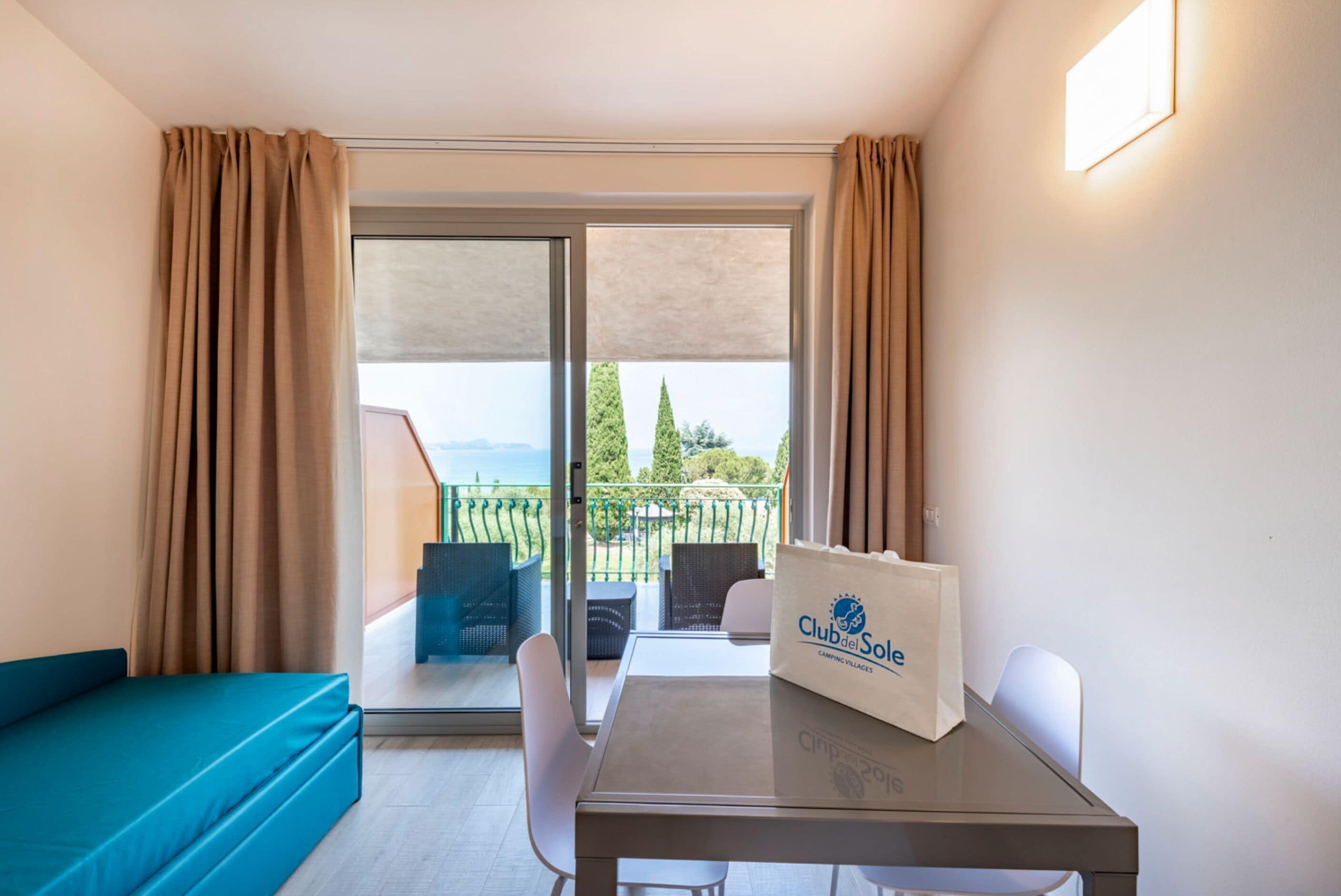 Een kamer met balkon, een tafel met tas en een bank.
