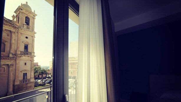 A view from a balcony with a historic building in the background. - Guesthouse San Domenico (Augusta)