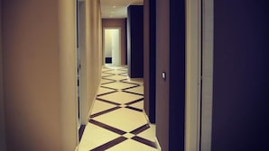 A hallway with a geometric patterned floor, beige walls, and a door at the end. - Guesthouse San Domenico (Augusta)