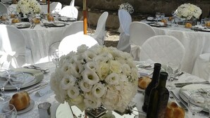 A table set for a formal event with white floral centerpieces, wine bottles, and bread rolls. - Villa Palazzola (Albano Laziale)