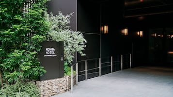 The exterior of Noriga Hotel, featuring a modern design with a stone wall and greenery.