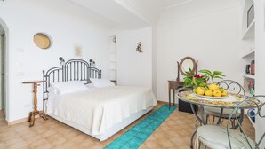 A bedroom with a bed, bedside table, and a small round table with chairs. - Elia's room: Double room with bathroom and shared terrace with sea view (Praiano)