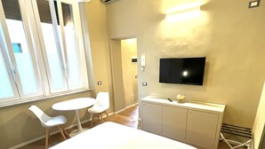 Una habitación de hotel con cama, escritorio, silla, televisor y ventana.