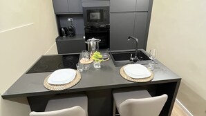 Una cocina moderna con armarios oscuros, una isla central con taburetes y un horno empotrado.