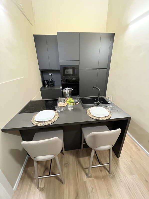A modern kitchen with dark cabinetry, a central island with bar stools, and a built-in oven.