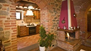 Una cocina rústica con paredes de ladrillo visto, armarios de madera y chimenea de ladrillo.