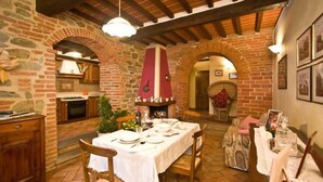 Un comedor rústico con pared de ladrillo, vigas de madera y una mesa preparada para una comida.