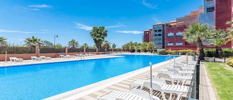 Una piscina con sillas de descanso y palmeras.
