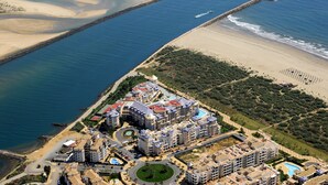 Luchtbeeld van een kusthotel met meerdere gebouwen, een strand en een jachthaven.