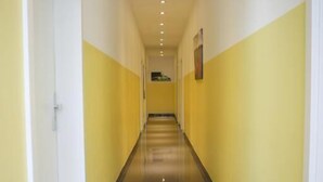A long, narrow hallway with yellow walls and a shiny floor, leading to a door at the end. - Franken Motel (Fuerth)