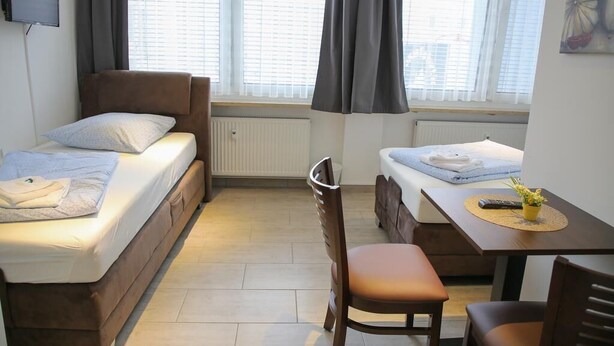 A compact bedroom with a single bed, a small table, and a chair. - Franken Motel (Fuerth)
