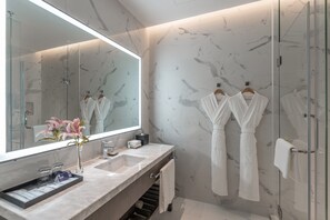 A modern bathroom with marble walls, a large mirror, two sinks, and two white robes hanging on hooks. - Hyatt Place Changsha Airport (Changsha)