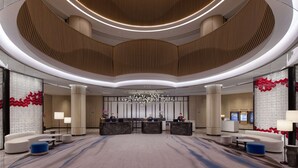 Eine moderne Hotelhalle mit gewölbter Decke, Empfangstresen, Sitzbereichen und einem dekorativen Kronleuchter.