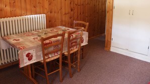 Ein Essbereich mit einem Tisch für vier Personen, Holzstühlen, einem Heizkörper und einem weißen Kleiderschrank.