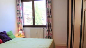 Une chambre à coucher avec un lit, un radiateur et des rideaux.