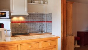 Une cuisine de taille réduite équipée d’un four à micro-ondes, d’un évier et de meubles de rangement en bois.
