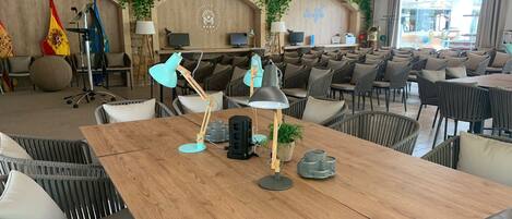A restaurant with a wooden table, wicker chairs, and a ceiling with wooden beams.