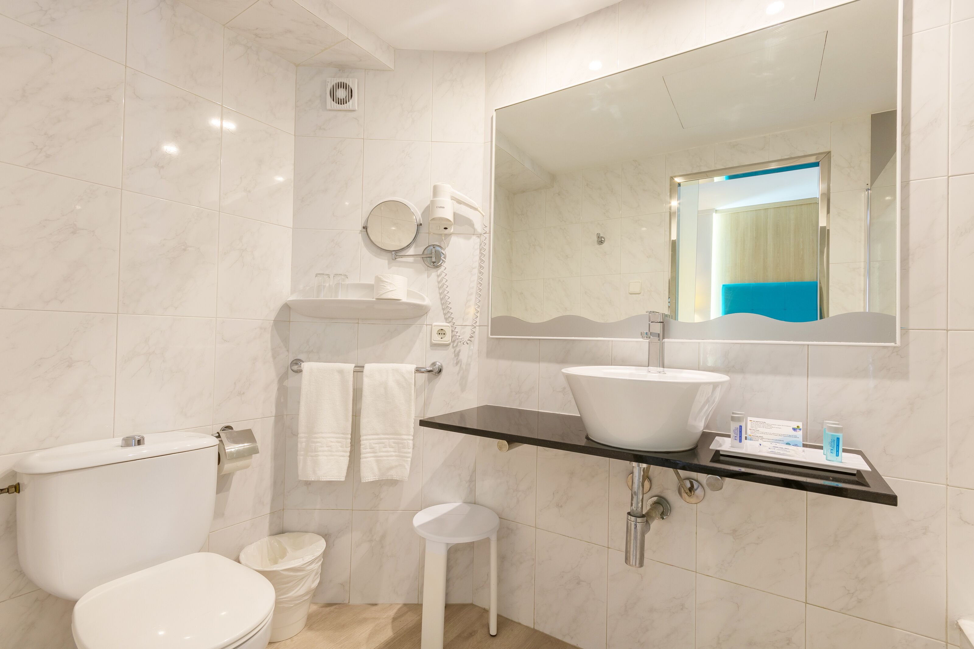 Ein modernes Badezimmer mit Toilette, Waschbecken und Spiegel.