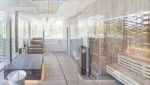 Een moderne hotel lobby met een glazen wand, een houten receptiebalie en een trap die naar de bovenverdieping leidt.
