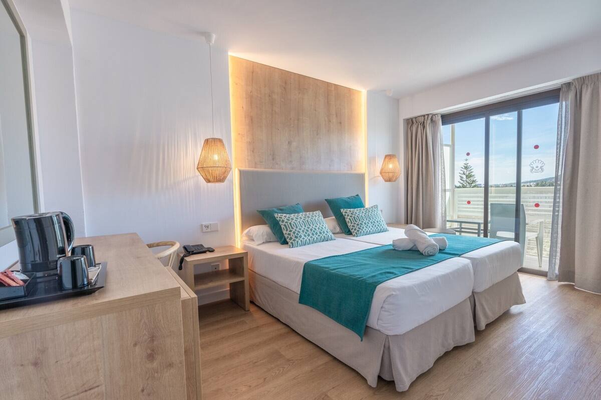 Een hotelkamer met een bed, nachtkastjes, een bureau en uitzicht.