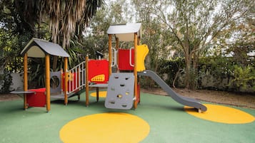 Un parque infantil con un tobogán, estructuras para escalar y una casita de juegos cubierta.