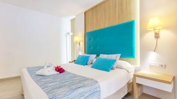Een moderne hotelkamer met een groot bed, een houten hoofdbord en twee bedlampjes.