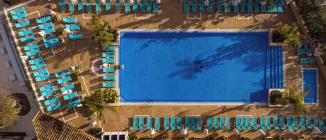An aerial view of a hotel pool area with multiple lounge chairs and a central swimming pool.