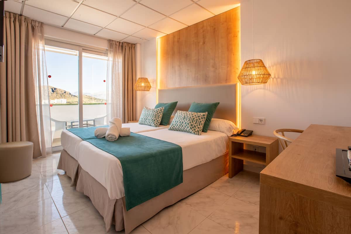 Hotelkamer met een groot bed, een bureau, een stoel, een nachtkastje en uitzicht op de omgeving.