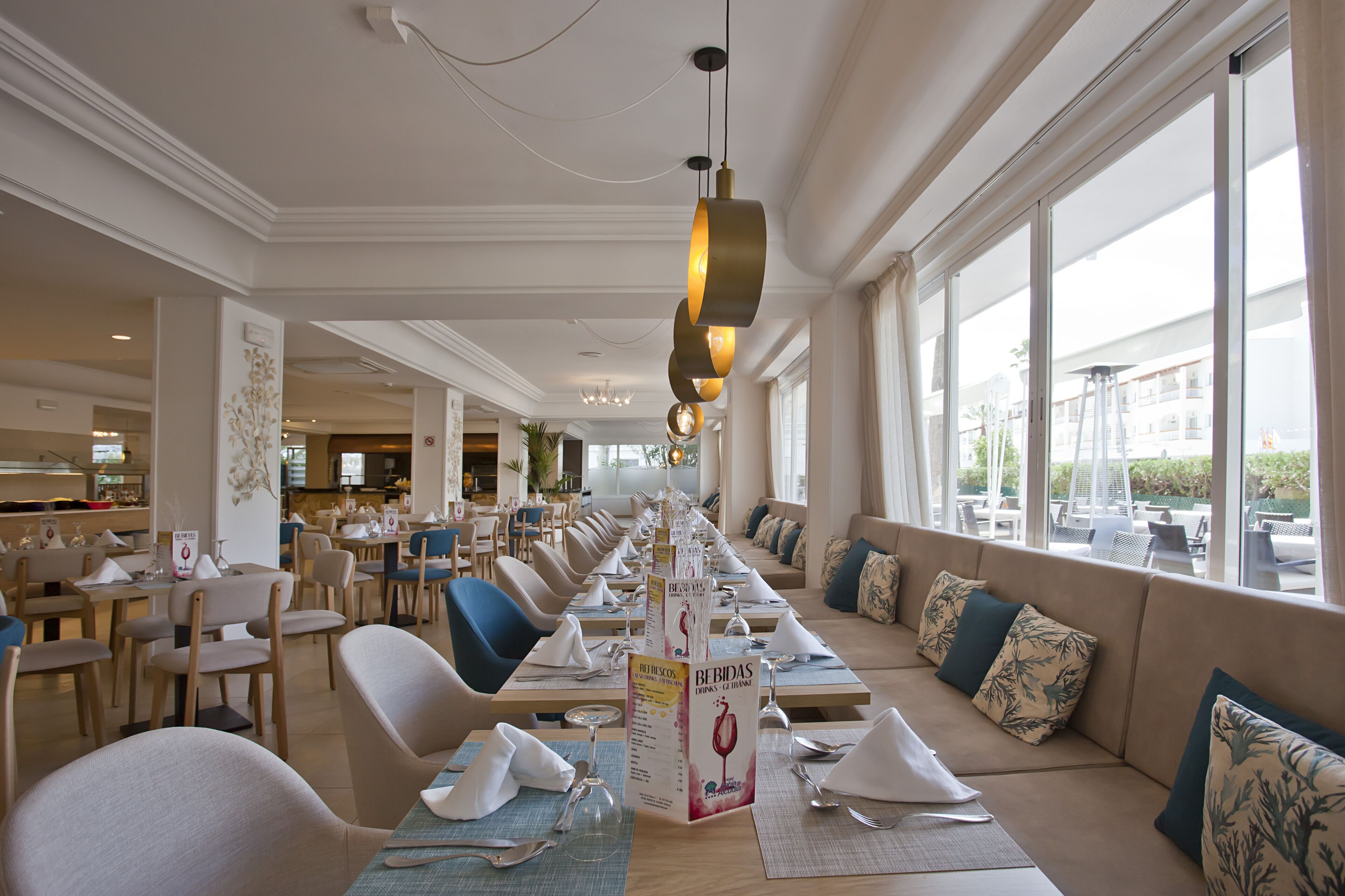 A restaurant with a long counter, multiple seating areas, and large windows.